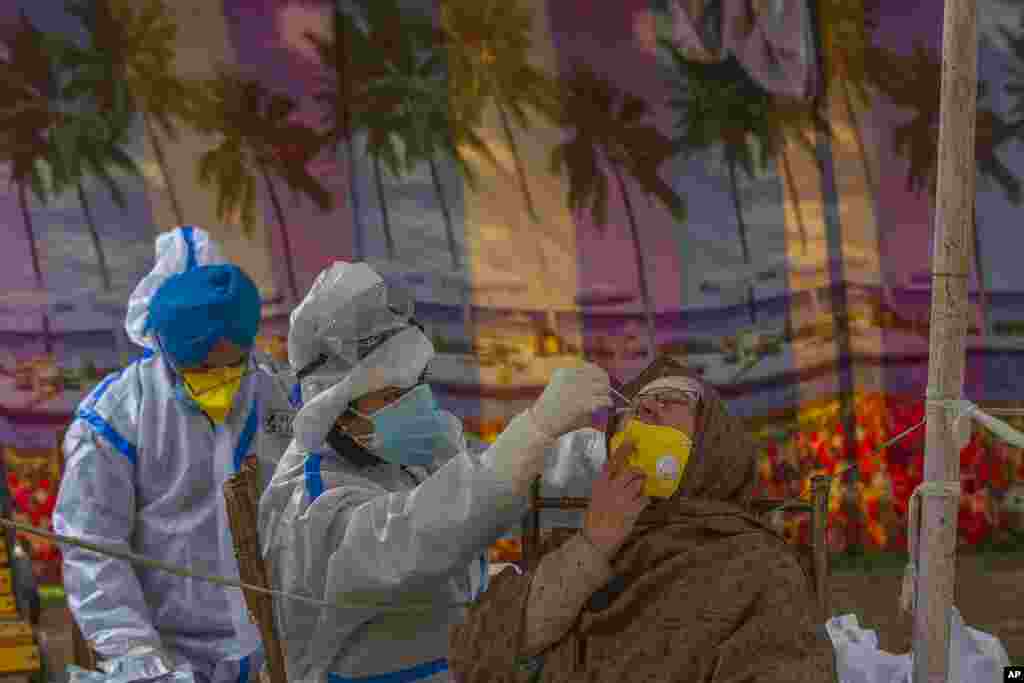 A health worker takes a nasal swab sample of a Kashmiri woman to test for COVID-19 in Srinagar, Indian-controlled Kashmir. India's total COVID-19 positive cases exceed 9.7 million, the second highest behind the United States.