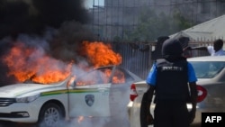 FILE - A Nigerian police officer watches a police vehicle burn after clashes with supporters of Islamic Movement of Nigeria protesting against the imprisonment of their leader, Ibrahim Zakzaky, in Abuja, Oct. 30, 2018.