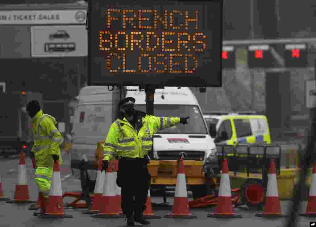 A police officer directs traffic at the entrance to the closed ferry terminal in Dover, England, after the Port of Dover was closed and access to the Eurotunnel terminal suspended following the French government's announcement. France banned all travel from the UK for 48 hours from midnight Sunday due to a new coronavirus strain.