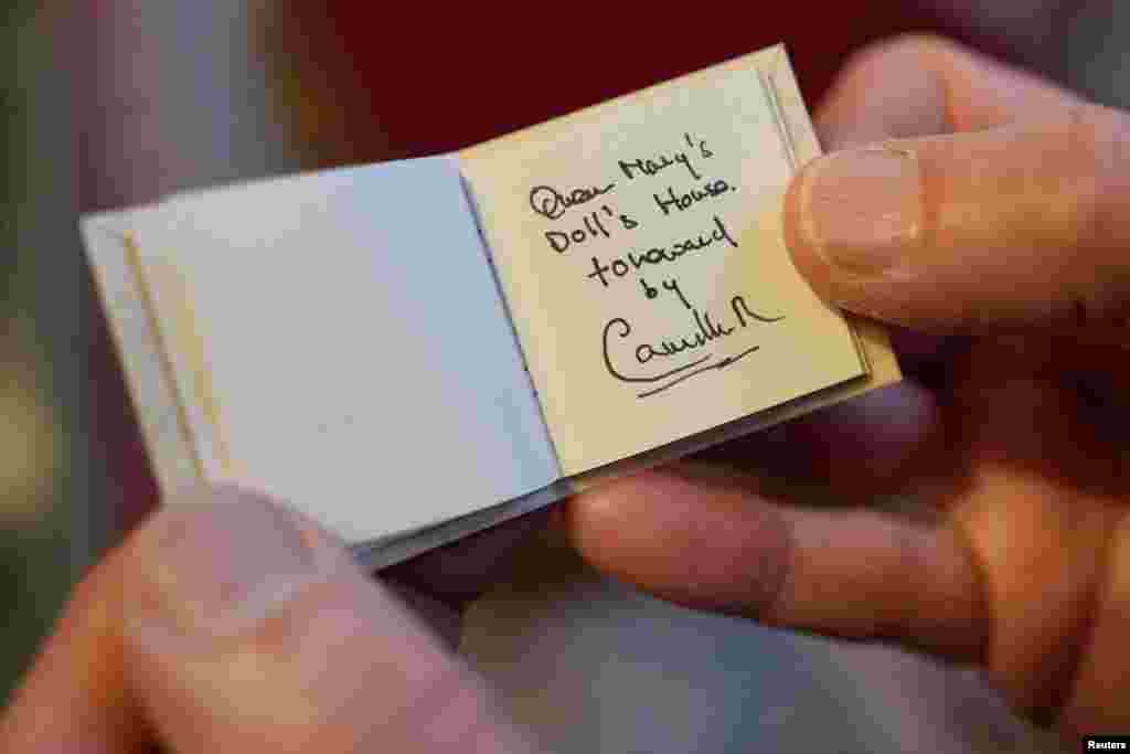 Glenn Bartley, head of the Royal Bindery, shows a miniature book, written by Britain's Queen Camilla, during a reception at Windsor Castle for authors, illustrators and binders who have been involved in the new Miniature Library collection displayed alongside Queen Mary's Dolls' House for visitors to enjoy throughout 2024 in celebration of its centenary year in Windsor. 