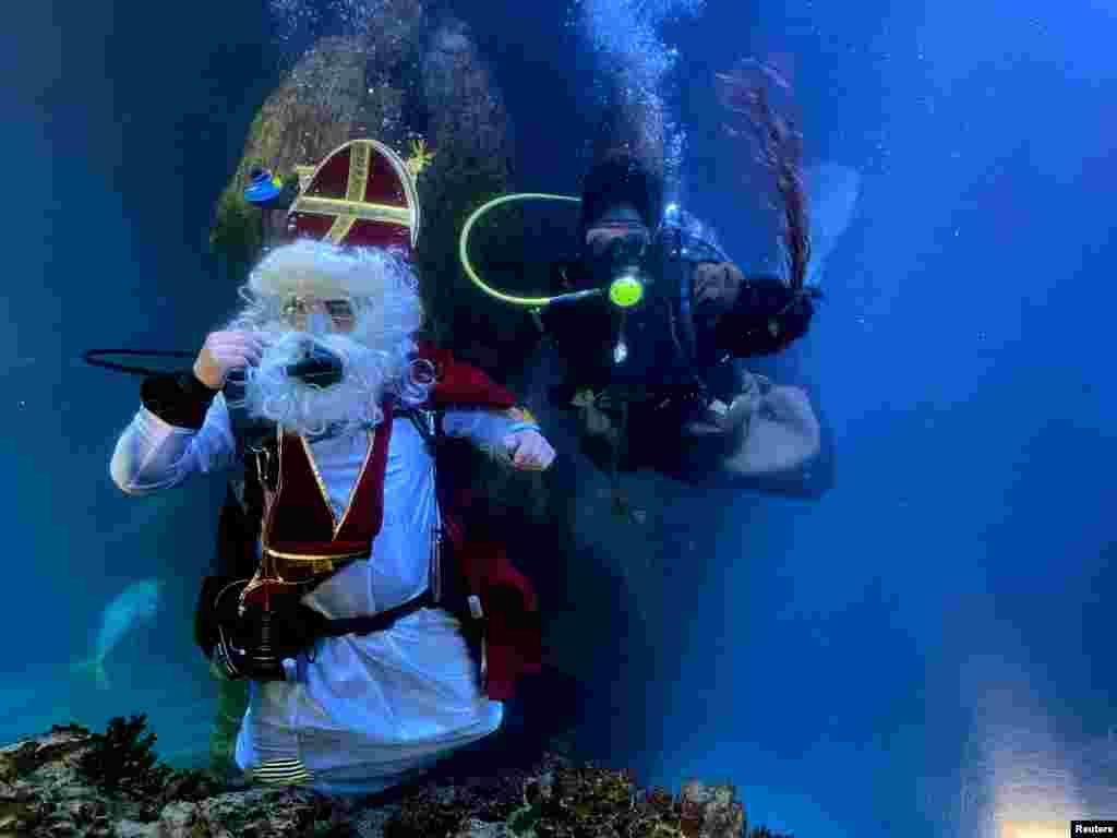 A diver dressed as Santa Claus and his helper "Knecht Ruprecht" pose inside a fish tank at the Sea Life aquarium in Munich, Germany.