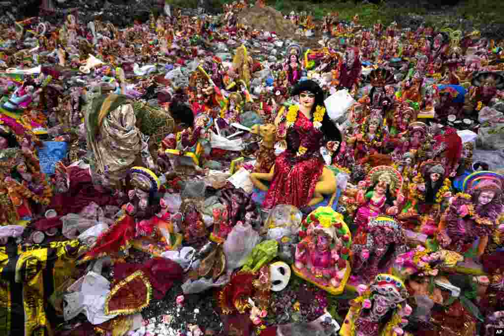 A woman searches for reusable material amid idols of Hindu goddess Dashama left by devotees on the banks of River Sabarmati in Ahmedabad, India.