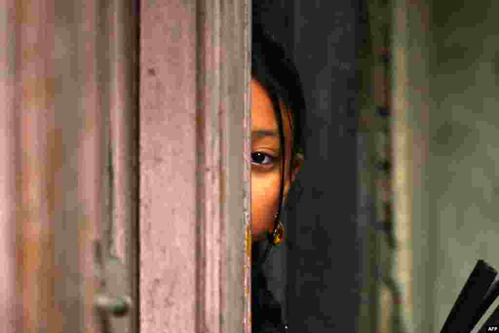 A girl watches the members of Nepali ethnic Newar community participating in Jyapu Day celebrations that mark the end of the harvest season, in Kathmandu.