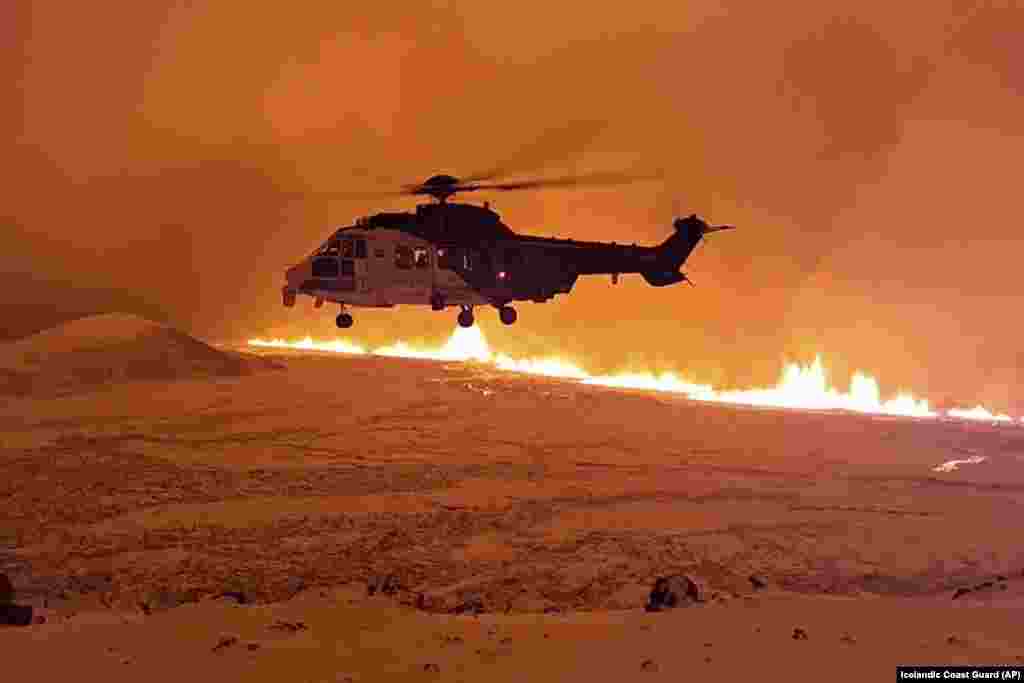 This image made from video provided by the Icelandic Coast Guard shows its helicopter flying near magma running on a hill near Grindavik on Iceland's Reykjanes Peninsula.