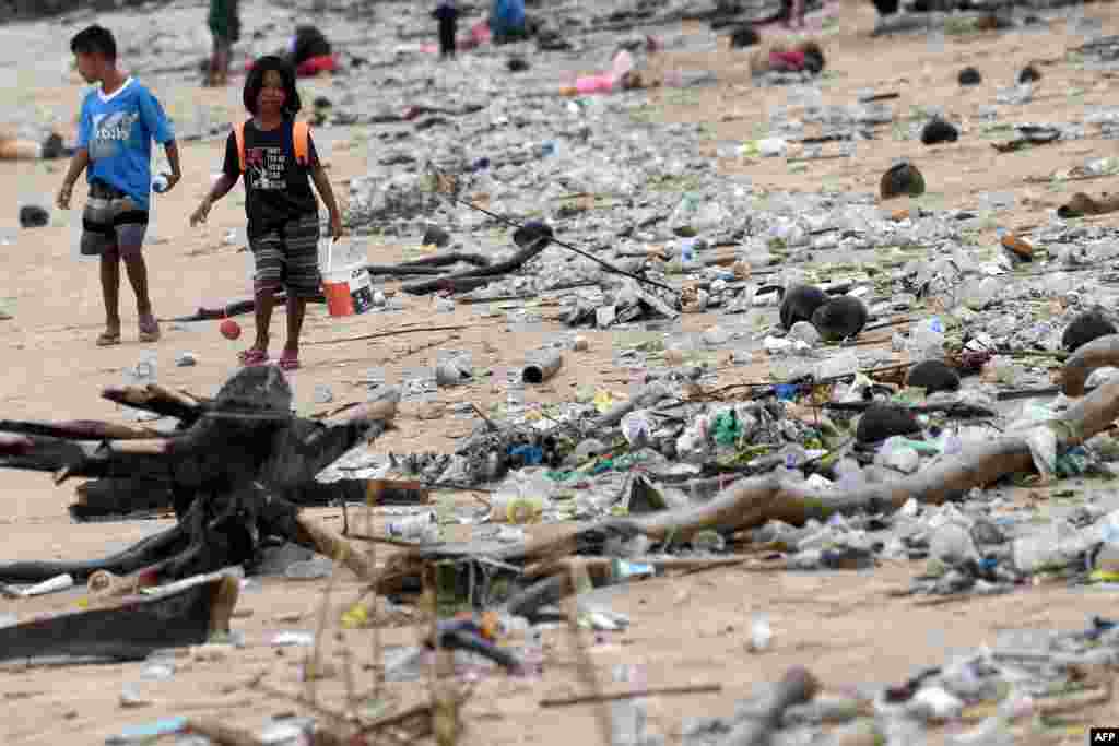 Children walk past plastic and other debris washed ashore at Kedonganan Beach, Badung regency, on Indonesia's resort island of Bali.