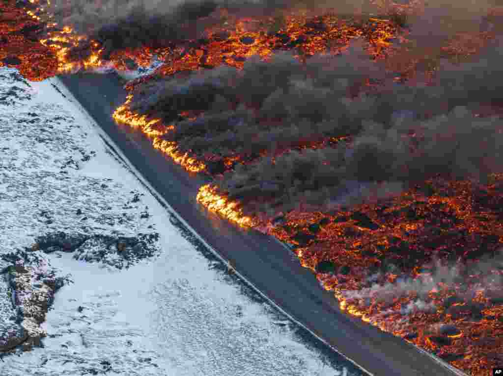A view of lava crossing the main road to Grindavík and flowing on the road leading to the Blue Lagoon, in Grindavík, Iceland. A volcano in southwestern Iceland has erupted for the third time since December and sent jets of lava into the sky.