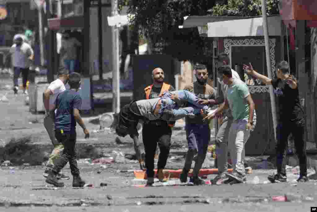 Palestinians carry a wounded man shot by Israeli forces shortly after he threw a bomb toward an Israeli army vehicle during a military raid in the Jenin refugee camp, a militant stronghold in the occupied West Bank.