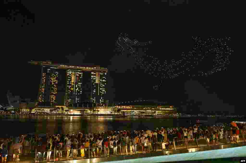 People gather to watch drones forming a dragon during a performance titled 'The Legend Of The Dragon Gate' above the Marina Bay waterfront on the first day of the Lunar New Year in Singapore, Feb. 10, 2024.
