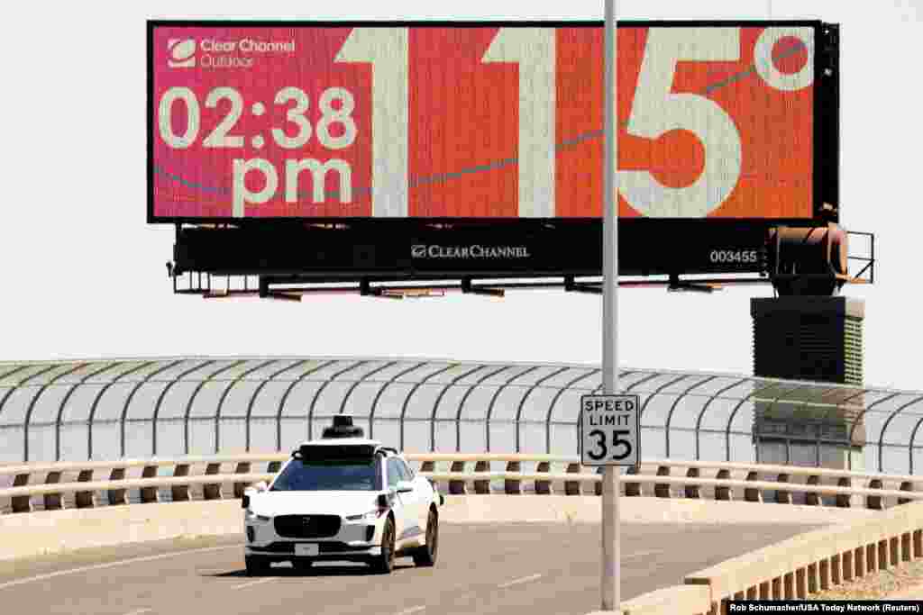 A Waymo self-driving car drives on Seventh Street as the temperature of 115 degrees is displayed on a digital billboard in downtown Phoenix, Arizona, July 17, 2023.
