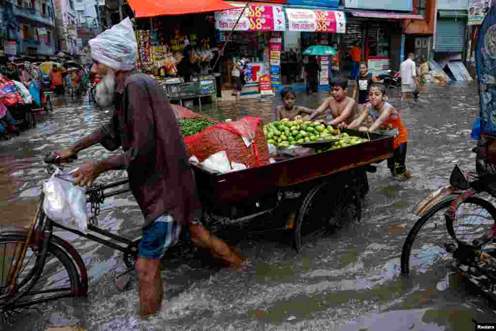 Children push a vegetable seller's cart as streets are flooded amid heavy rains in Dhaka, Bangladesh.