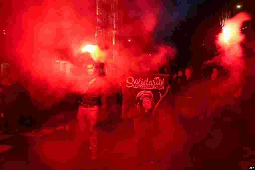 Protesters light flares during a solidarity march for the defense of immigrants against France's new immigration law at Theodor Herzl Square, in Paris.