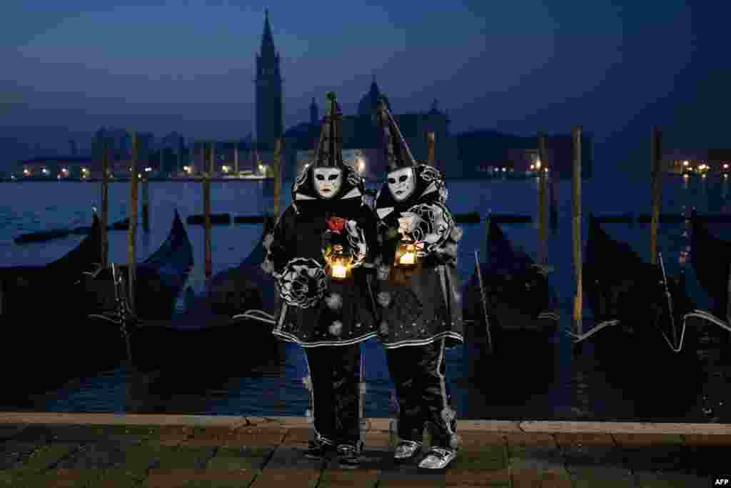 Masked revelers wearing period costumes pose during the traditional Venice Carnival, Italy.