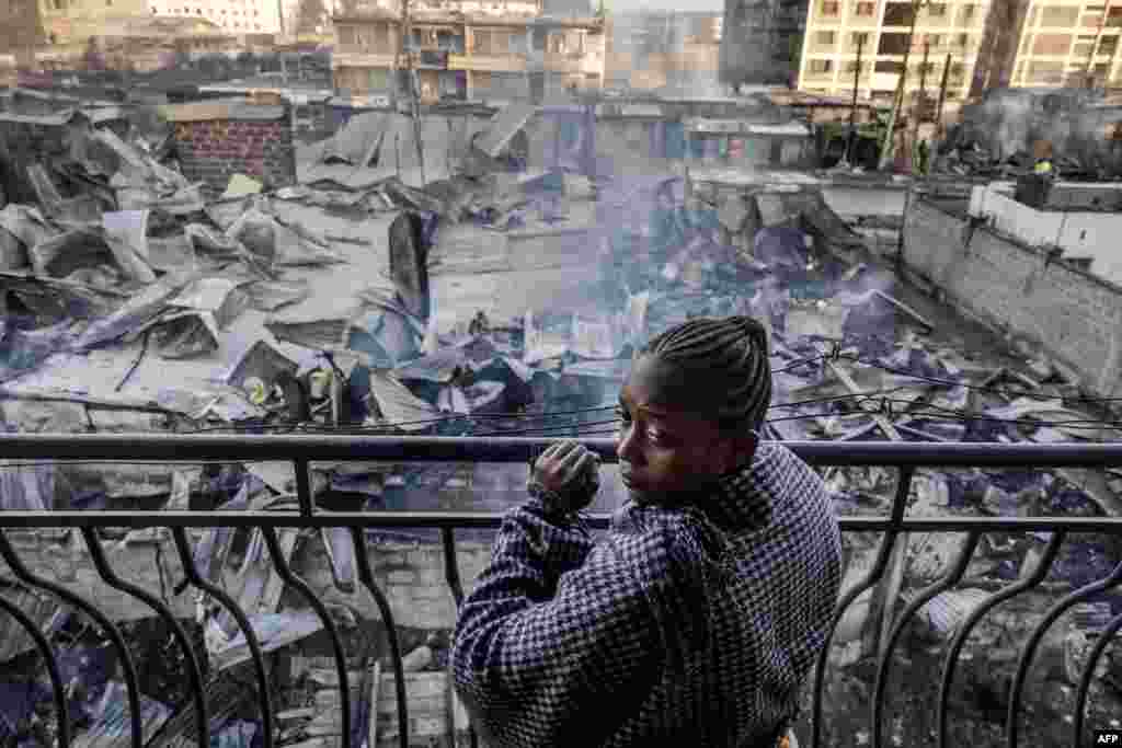A woman looks from a balcony at the heavily damaged houses and shops, a day after a gas explosion in the Embakasi area of Nairobi.