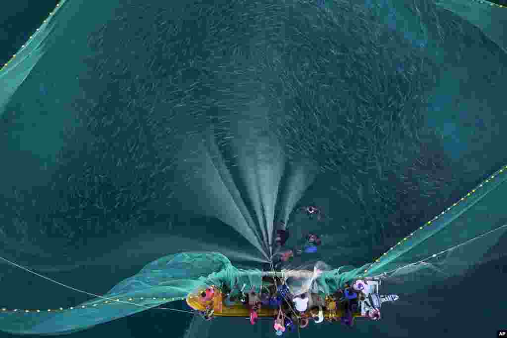 Fisherwomen and men pull in a net of fish off the coast of Chuao, Venezuela.