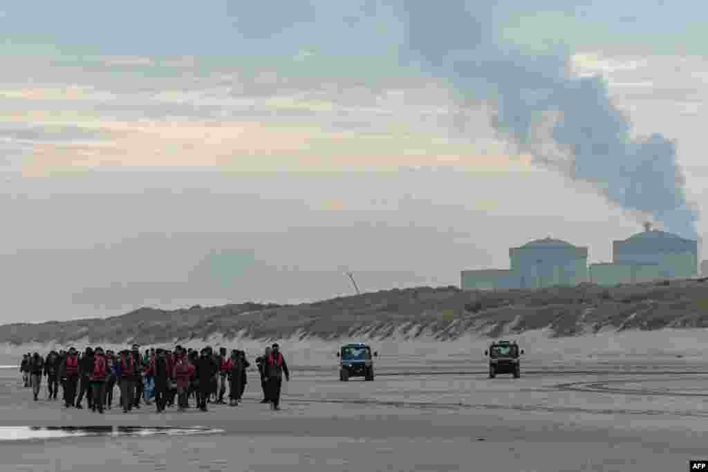 Migrants return inland after being prevented from boarding smugglers' boats by French National Police on the beach of Gravelines, northern France.
