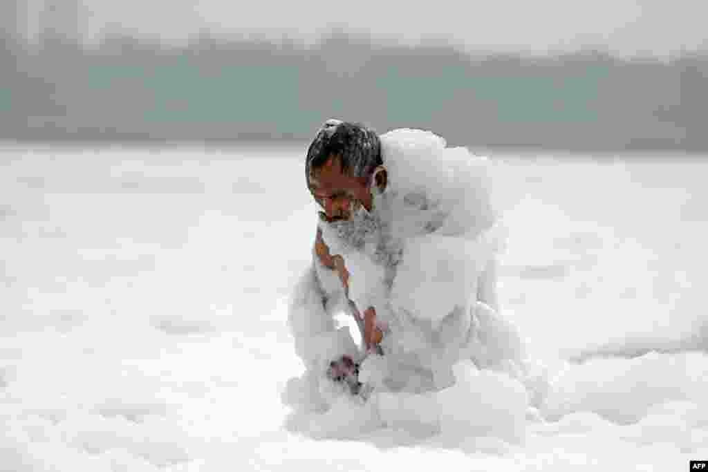 A man bathes in the polluted waters of river Yamuna laden with foam in New Delhi, India.