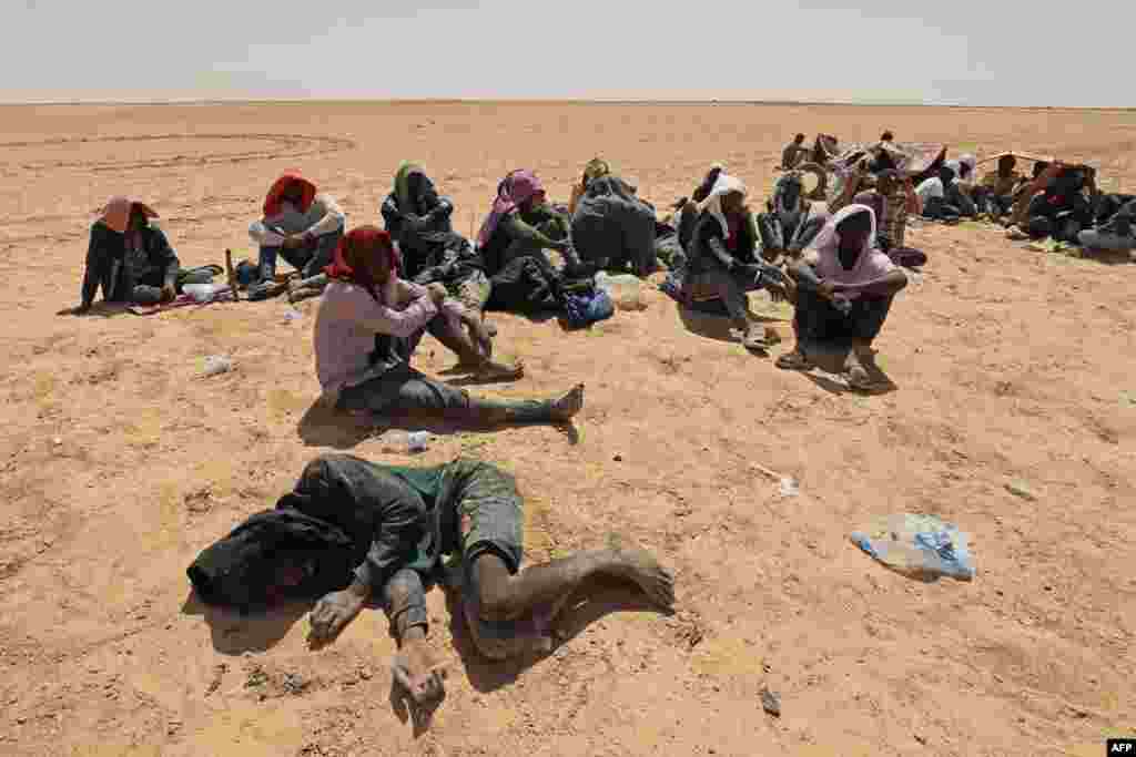 Migrants from sub-Saharan African countries who claim to have been abandoned in the desert by Tunisian authorities without water or shelter, sit in an uninhabited area near Libya's border town of Al-Assah.
