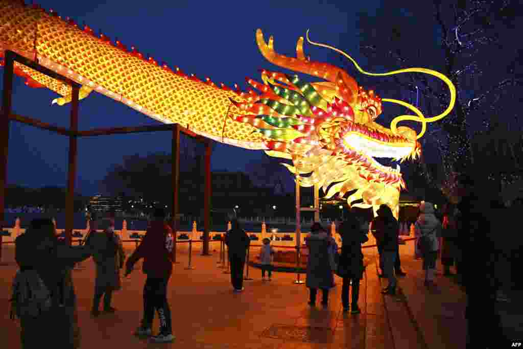 People gather to look at a giant dragon figure at a park in Beijing, on the eve of the Lunar New Year of the Dragon.