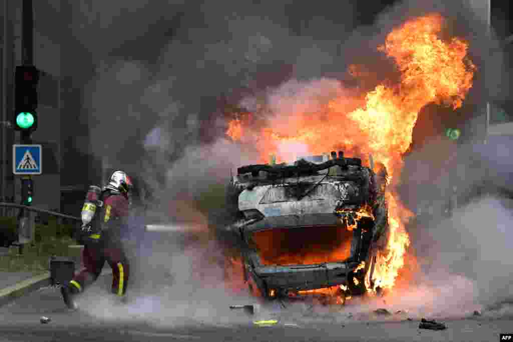 A firefighter extinguishes a burning car at the end of a commemoration march for a teenage driver shot dead by a policeman, in the Parisian suburb of Nanterre. Violent protests broke out in France as anger grows over the police killing of a teenager, with security forces arresting 150 people in the chaos that saw balaclava-clad protesters burning cars and setting off fireworks. 