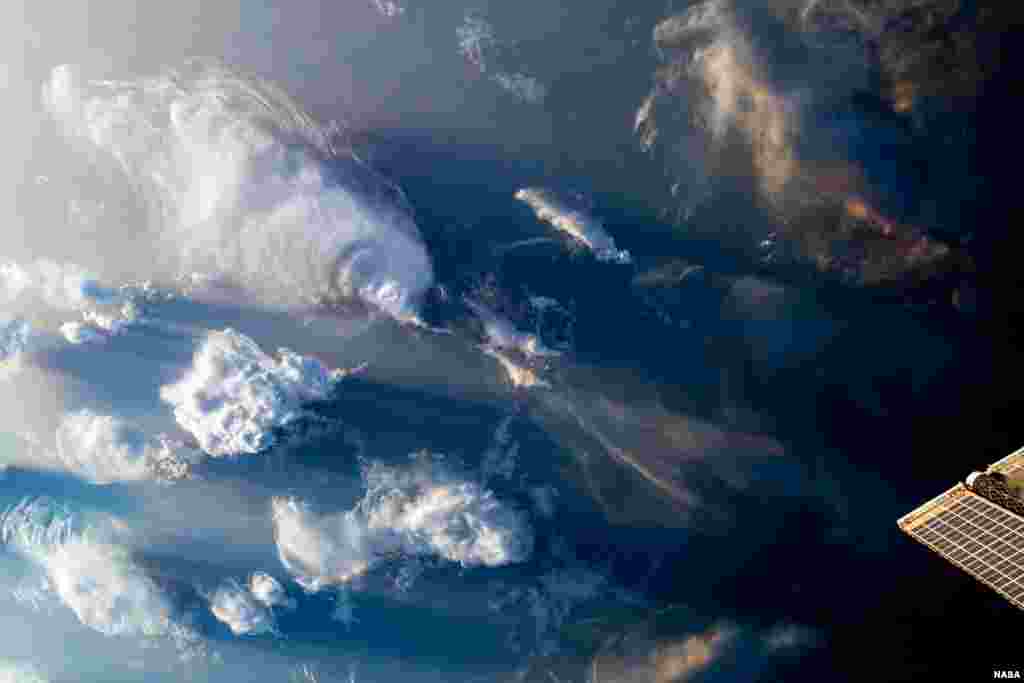 As the International Space Station orbited 259 miles above North Africa, clouds covered the sky, in this image taken July 13, 2023, released by NASA. To the bottom right of the image, one of the station's roll-out solar arrays peeks through.