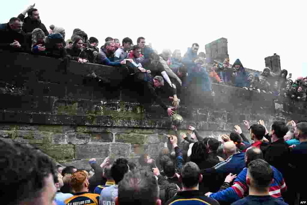 Competitors from the Up'ards and the Down'ards fight for the ball during the annual Royal Shrovetide Football Match in Ashbourne, northern England.