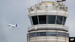 Sebuah pesawat jet penumpang melintasi di depan menara pengawas Administrasi Penerbangan Federal AS (FAA) di Bandara Nasional Ronald Reagan, Washington, 24 Maret 2011. (Foto: Cliff Owen/AP, arsip)