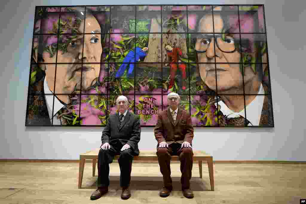 Gilbert and George sit with their artwork called On The Bench in their exhibition called The Paradisical Pictures at the opening of The Gilbert & George Centre in east London.