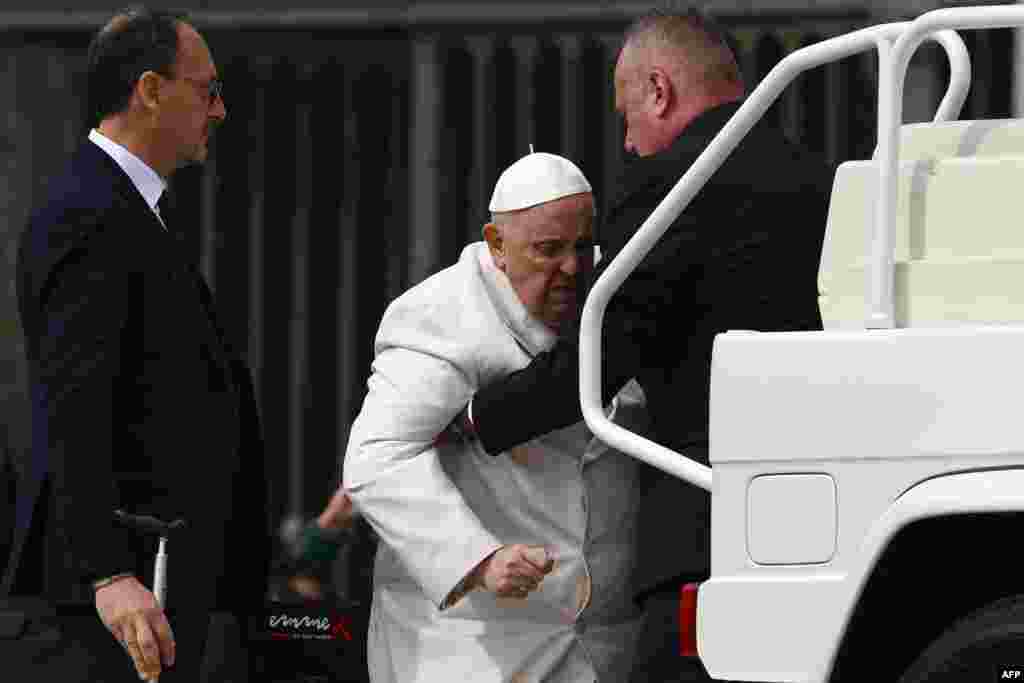 Pope Francis is helped to get on the popemobile car at the end of the weekly general audience at St. Peter's square in The Vatican.