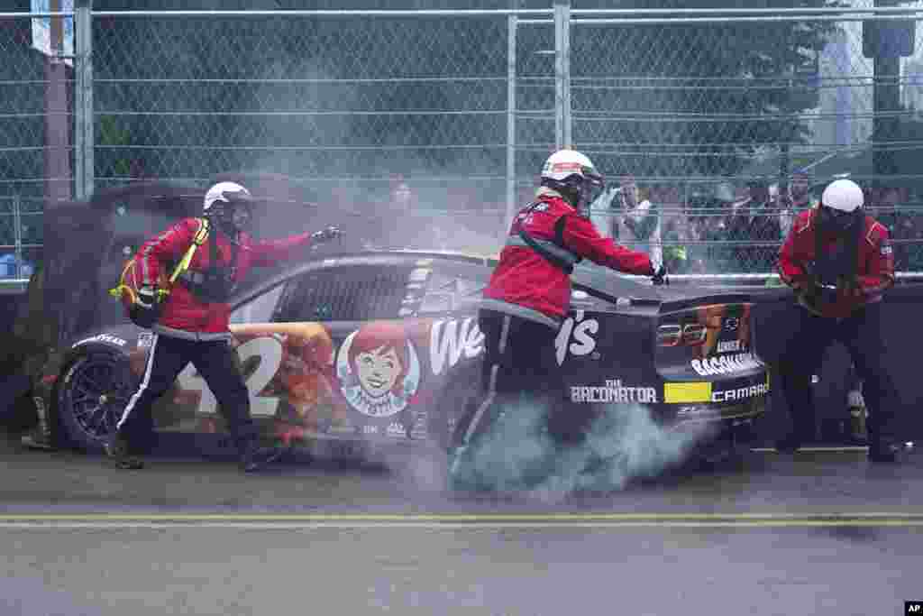 Track safety workers assist Noah Gragson after he crashed into a tire barrier during a NASCAR Cup Series auto race at the Grant Park 220, July 2, 2023, in Chicago, Illinois.