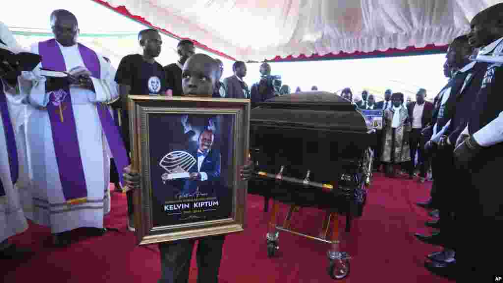 Caleb Kigen, son of marathon record holder Kelvin Kiptum, holds his late father's portrait ahead of his burial in Elgeyo Marakwet, Kenya. Kelvin Kiptum died in a road accident on Feb. 11, 2024.