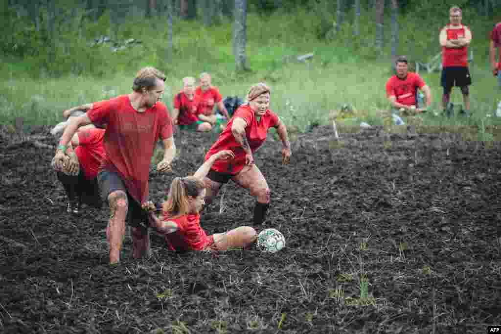 Players vie for the ball during a match of swamp soccer, July 15, 2023 at the Swamp Soccer World Cup in the swamps of Vuorisuo in Hyrynsalmi municipality, Finland.