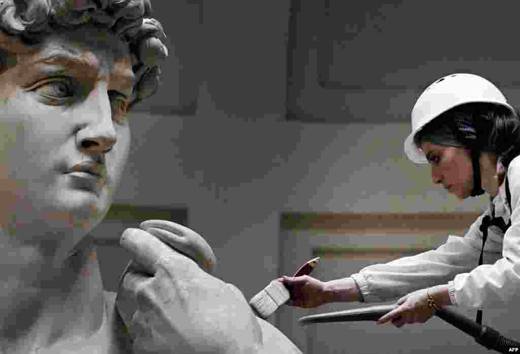Italian restorer Eleonora Pucci cleans Michelangelo's statue of David using a backpack vacuum and synthetic fiber brush at the Galleria dell'Accademia, in Florence.