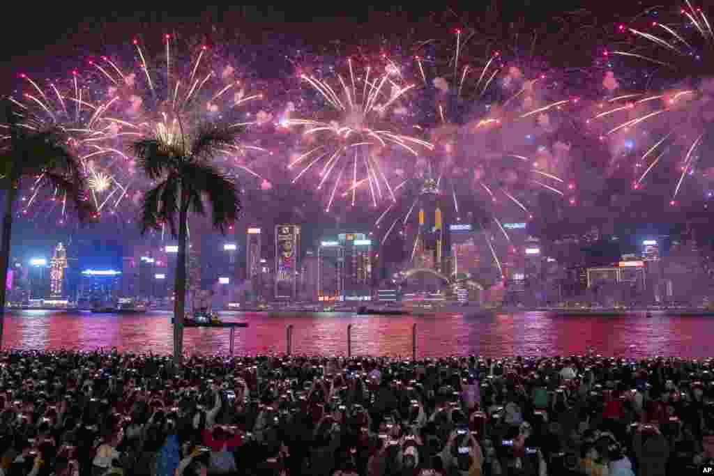 People watch fireworks lighting up over Victoria Harbour on the second day of the Lunar New Year of the Dragon, in Hong Kong.