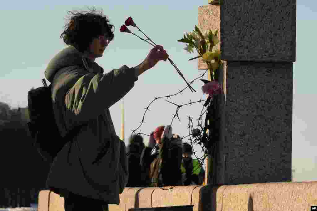 A woman places flowers as people pay tribute to Alexei Navalny at the Memorial to Victims of Political Repression in St. Petersburg, Russia.