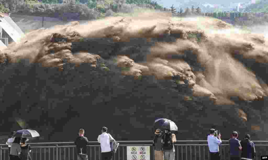People watch water and sand being released from the Xiaolangdi Reservoir Dam in Jiyuan, in China's central Henan province.
