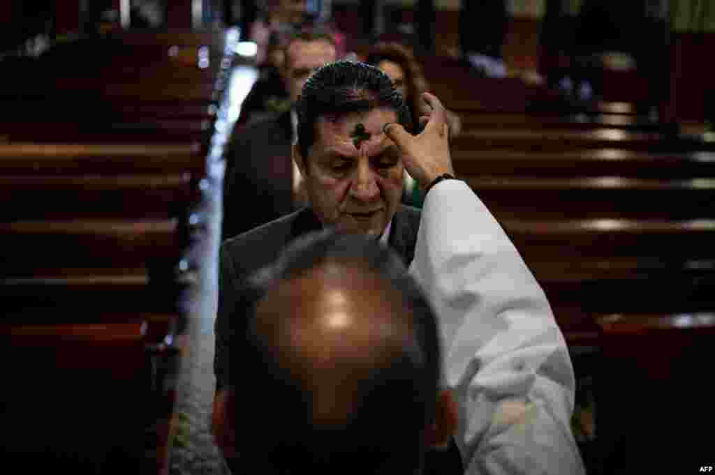 A priest makes the sign of the cross on the forehead of a man during the celebration of Ash Wednesday in Bogota, Colombia.