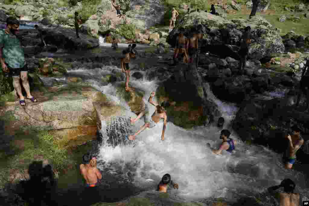 People cool off in a stream on a hot summer day along the outskirts of Srinagar, Indian-controlled Kashmir.