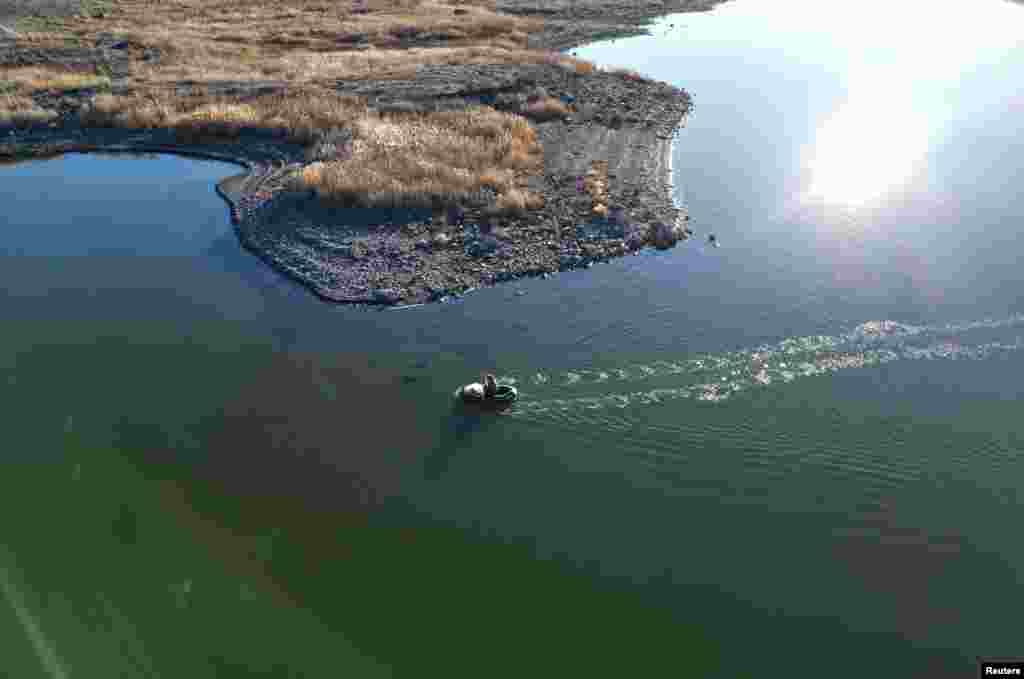 A man sails a boat on Lake Chagan, formed in 1965 as a result of a nuclear explosion at the Semipalatinsk Test Site, one of the main locations for nuclear testing in the Soviet Union, in the Abai Region, Kazakhstan.