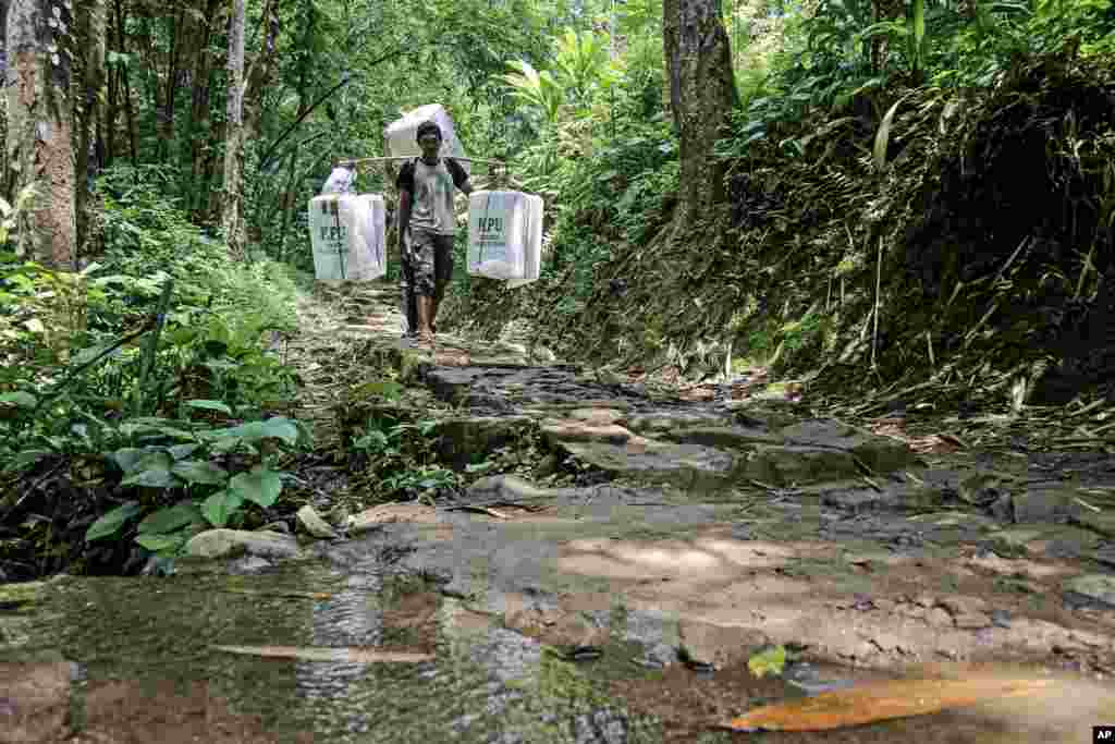 People carry ballot boxes to be distributed to polling stations ahead of the Feb. 14 election, in Kanekes village, Indonesia.