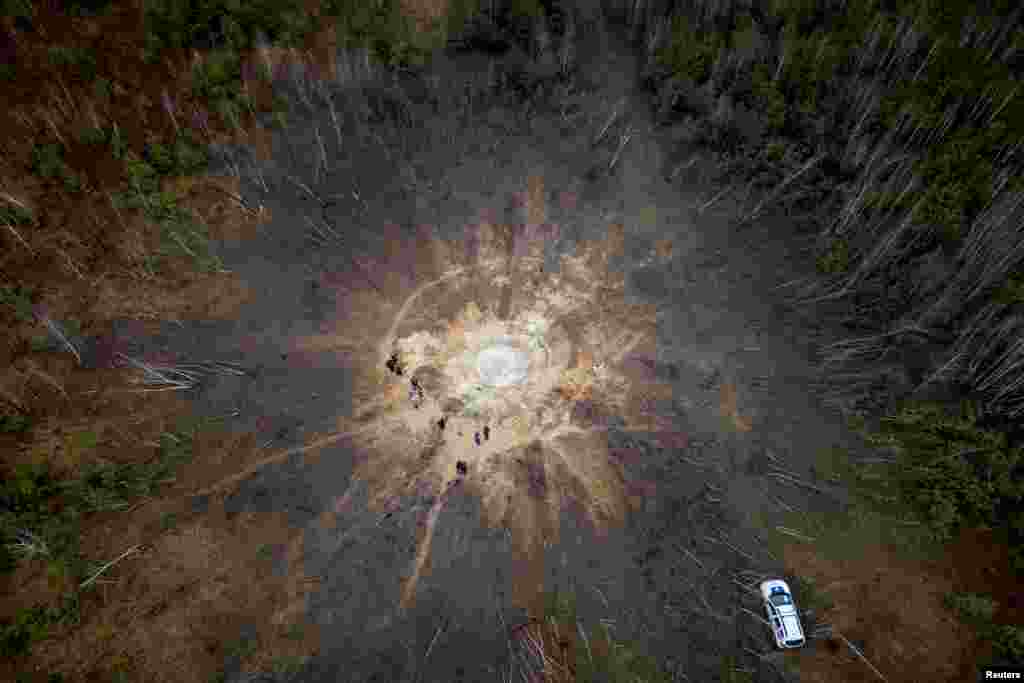 People stand around a crater caused by a Russian missile strike in the village of Buda-Babynetska, outside Bucha, near Kyiv, Ukraine.