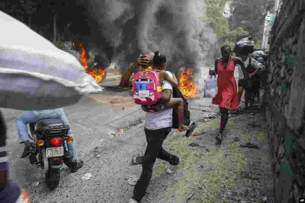 People walk past burning tires during a protest against Haitian Prime Minister Ariel Henry in Port-au-Prince, Feb. 5, 2024. Banks, schools and government agencies closed in Haiti’s northern and southern regions as protesters blocked main routes with blazing tires and paralyzed public transportation, according to local media reports. 