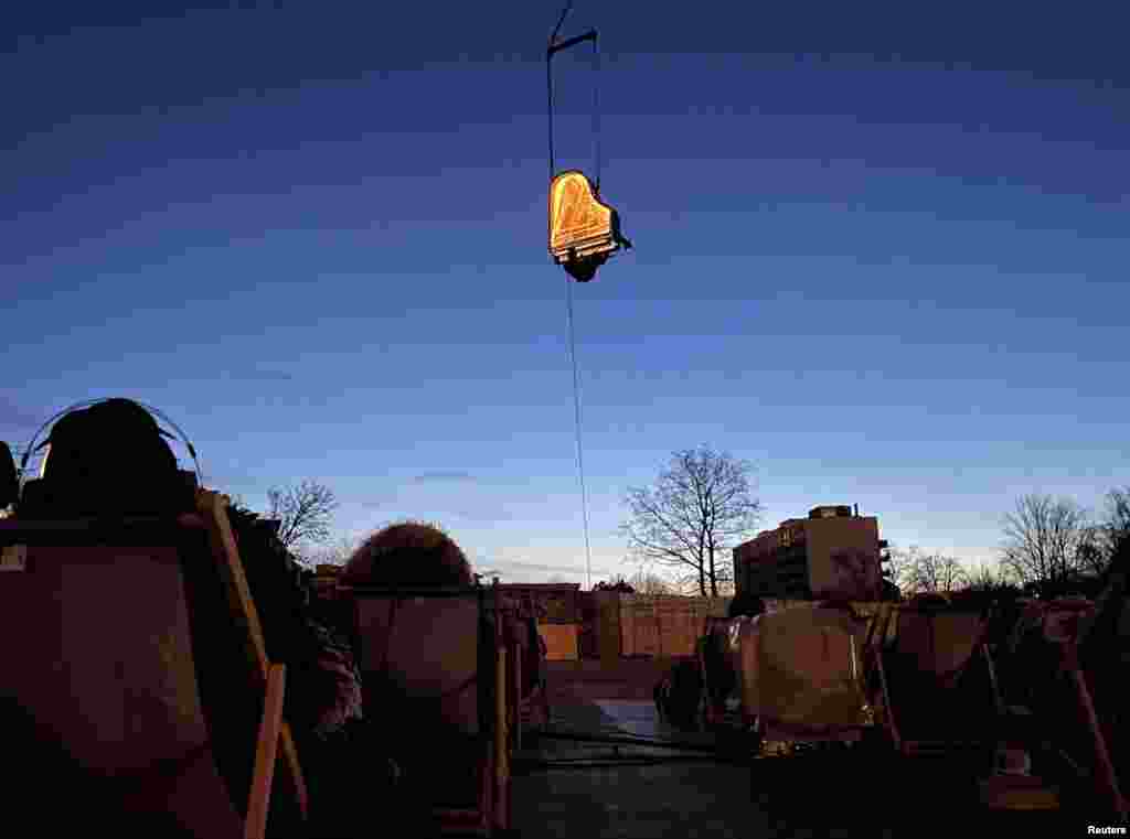 Swiss artist Alain Roche plays the piano hanging from a crane during a concert in Munich, Germany.