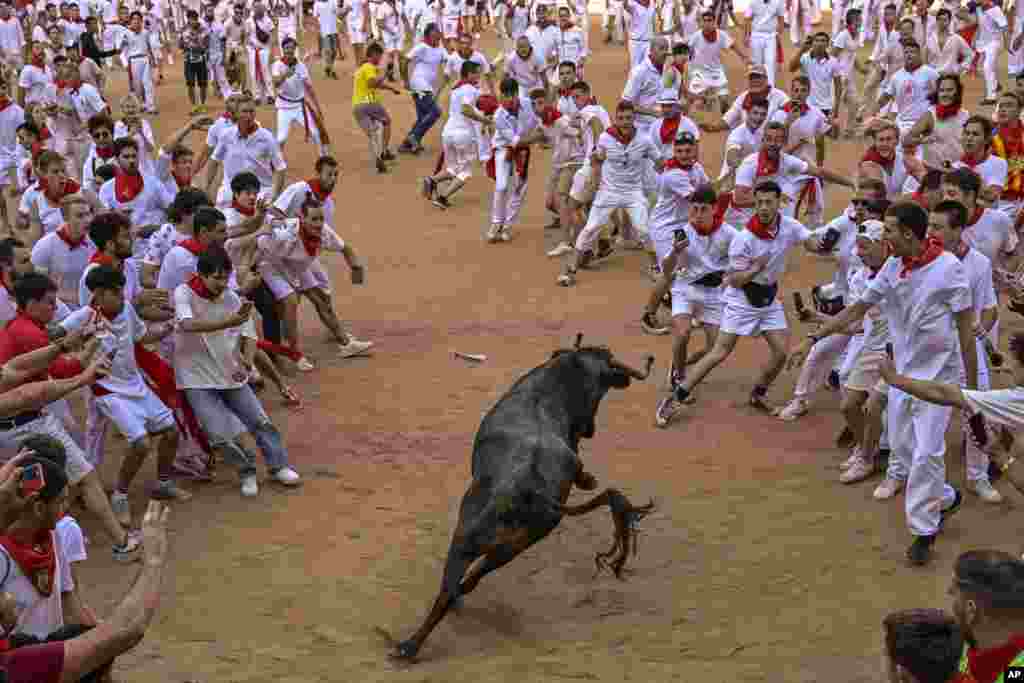 Revelers stand the bull ring at the end of the fourth running of the bulls during the San Fermin fiestas in Pamplona, Spain.