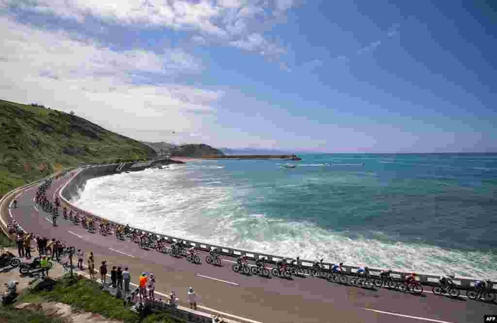 The pack of riders cycles along the Bay of Biscay coastline, near Getaria, in the Basque region of Northern Spain, during the 3rd stage of the 110th edition of the Tour de France cycling race, 193,5 km between Amorebieta-Etxano in Northern Spain and Bayonne in southwestern France.