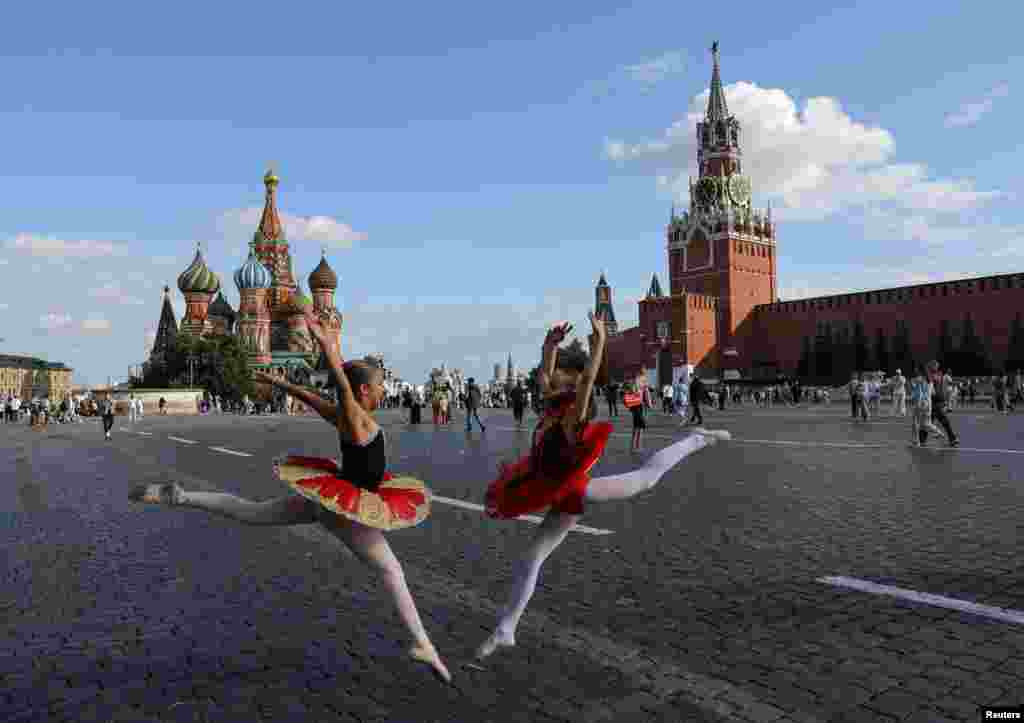 Girls in ballet dresses pose near St. Basil's Cathedral and the Kremlin's Spasskaya Tower in Red Square in central Moscow, Russia.