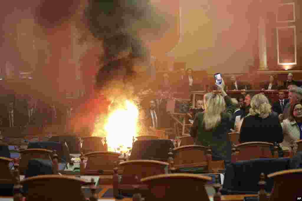 Democratic lawmakers throw a flare during a parliament session in Tirana, Albania. Opposition lawmakers disrupted the Parliament's session again to protest against what they say, is increasingly authoritarian rule by the governing Socialists. 