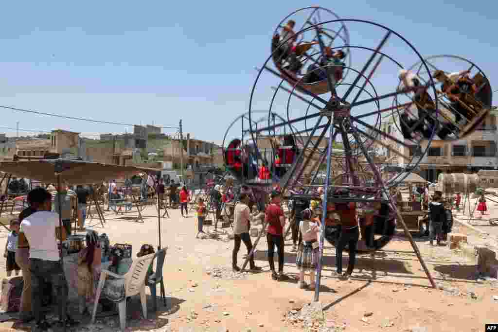 Children sit in an amusement ride on the first day of the Muslim feast of Eid al-Adha in Syria's rebel-held city of Binnish in the northwestern province of Idlib.