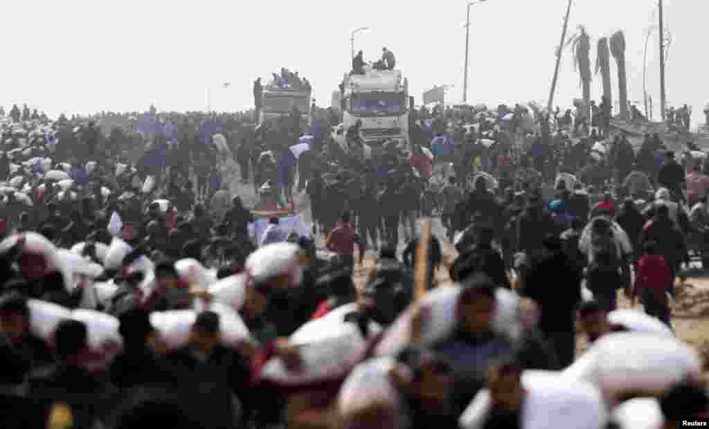 Palestinians carry bags of flour they grabbed from an aid truck near an Israeli checkpoint, as Gaza residents face crisis levels of hunge.