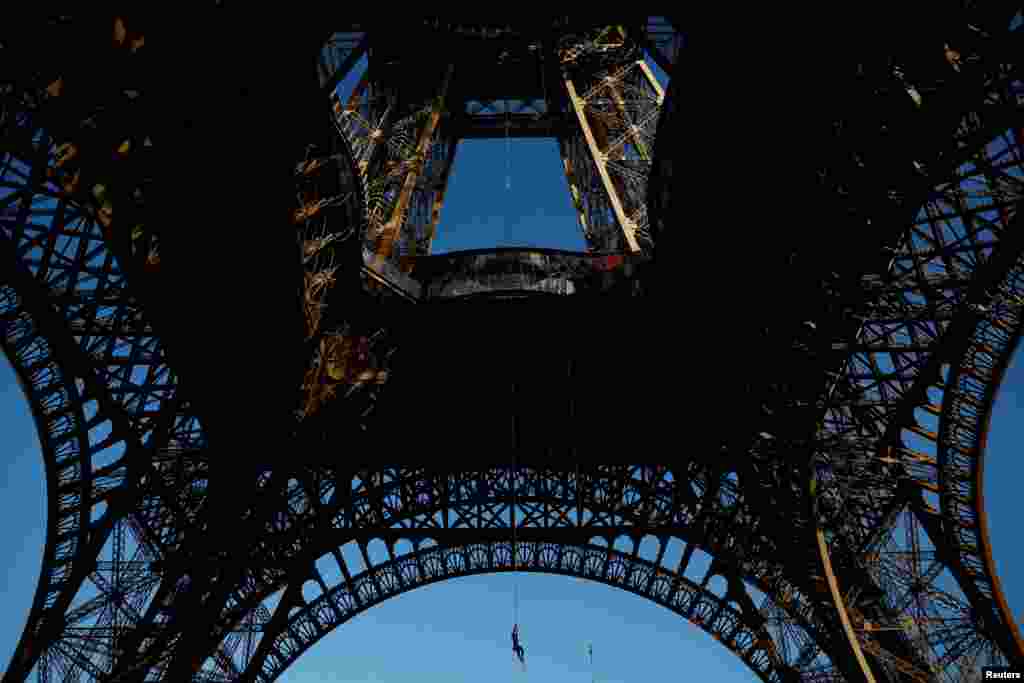 Athlete and Olympics torch bearer Anouk Garnier climbs a 110-meter-long rope launched in the center of the Eiffel Tower square to reach the 2nd floor and to attempt to break the world record for rope climbing, in Paris, France.