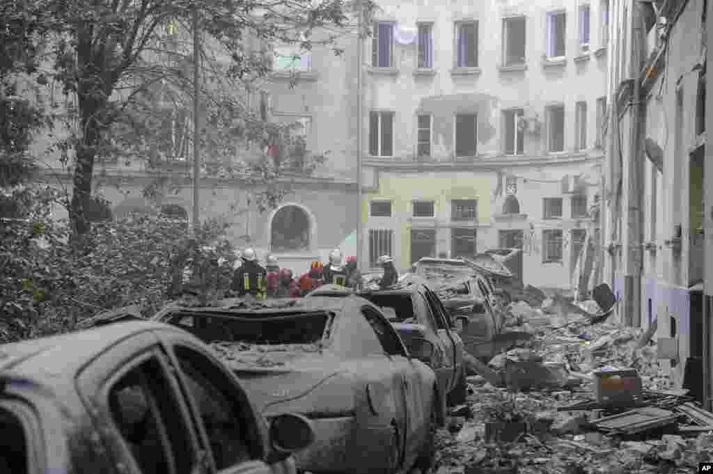 Emergency service workers gather outside damaged buildings as search for victims continues following a Russian missile attack in Lviv, Ukraine.